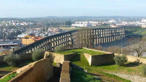 Amoreira-akvedukten löper i flera rader av bågar över torr mark utanför Elvas, med stadens vitkalkade hus bakom