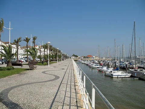 Marinan i Vila Real de Santo António med förtöjda segelbåtar och en stenlagd promenad med palmer längs kajen