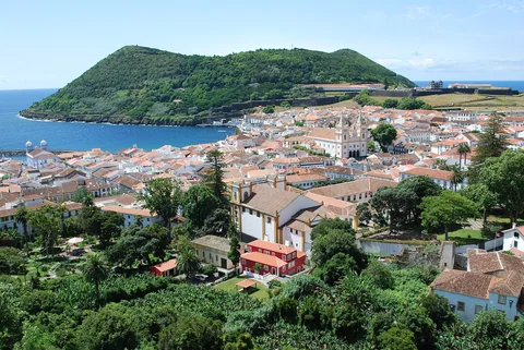 Angra do Heroísmo med vita hus och orange tegeltak längs bukten, med den gröna vulkankullen Monte Brasil bakom