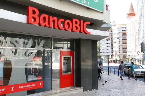 En bankfilial i gatuplan i Lissabon med stor röd skylt och en röd uttagsautomat infälld i fasaden