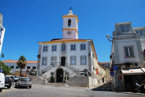 Vitt kommunhus med klocktorn och portugisisk flagga vid ett torg