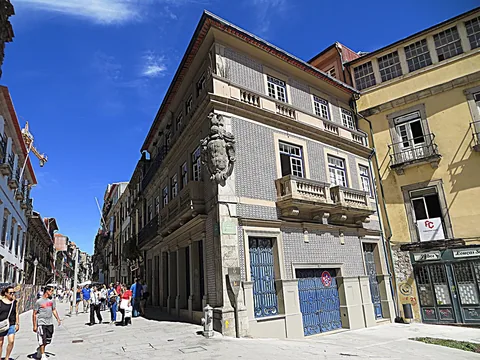 Gathörn i Portos gamla stad: en fasad klädd i grå azulejos med butikslokaler i bottenvåningen och bostadsvåningar med balkonger ovanför