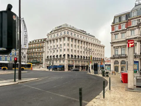 En vit hotellbyggnad i klassisk stil med rader av fönster och balkonger vid ett torg med breda gator