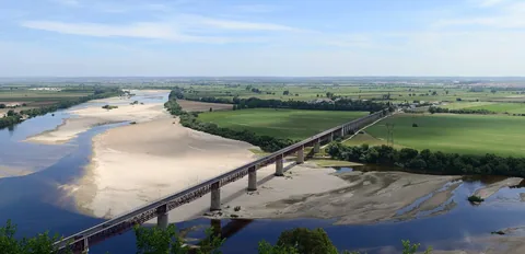 Utsikt från klippkanten i Santarém över Tejos breda sandbankar, den långa järnbron och den gröna slätten bortom