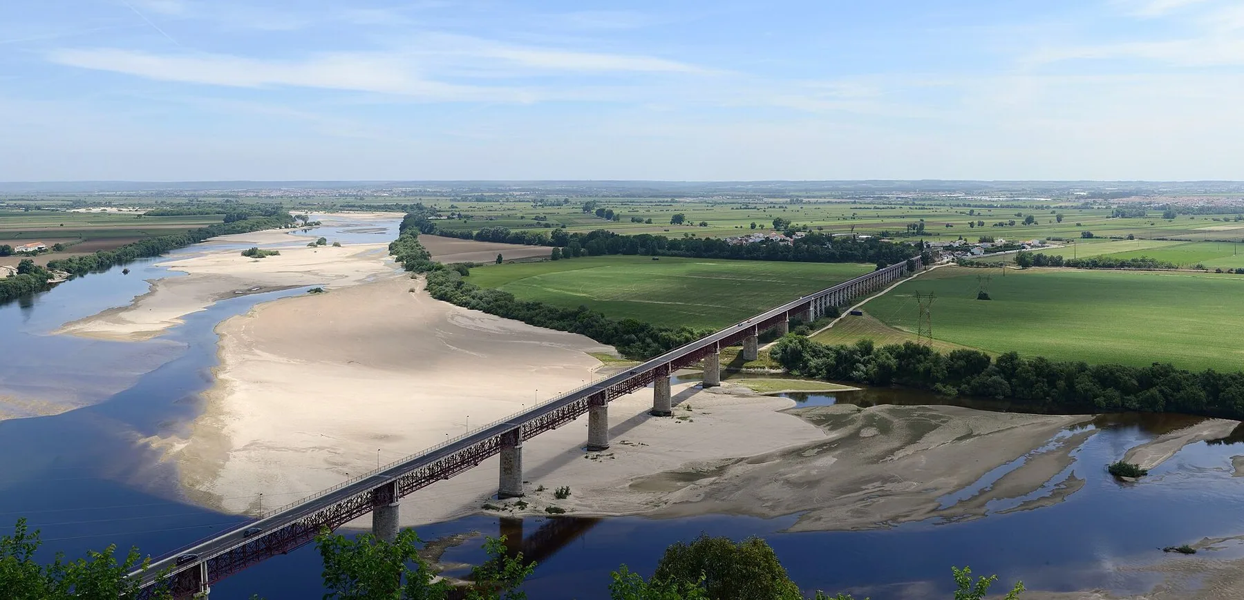 Utsikt från klippkanten i Santarém över Tejos breda sandbankar, den långa järnbron och den gröna slätten bortom