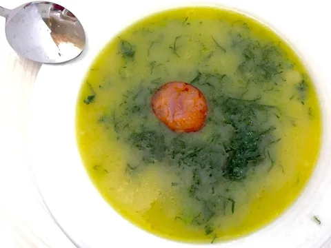 En djup tallrik caldo verde: krämig potatissoppa med fint strimlad grönkål och en skiva chouriço mitt i