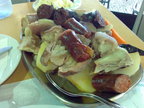 Cozido à portuguesa på ett uppläggningsfat: kokt fläsk och kyckling med potatis, morot och kål, med bitar av chouriço och blodkorv ovanpå