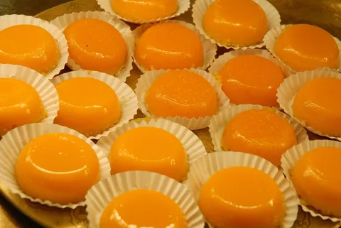 Ett fat med små bakverk av äggula i pappersformar, blanka och djupt orange