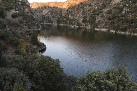Douro rinner mörk och stilla mellan branta klippsidor med gles buskvegetation i den djupa gränsravinen