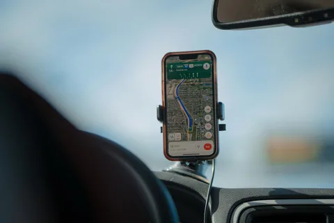 Mobiltelefon i hållare på en instrumentbräda som visar en navigationskarta