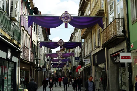 Handelsgata i Braga med lila draperier och kors hängda tvärs över gatan och butiker i bottenvåningarna