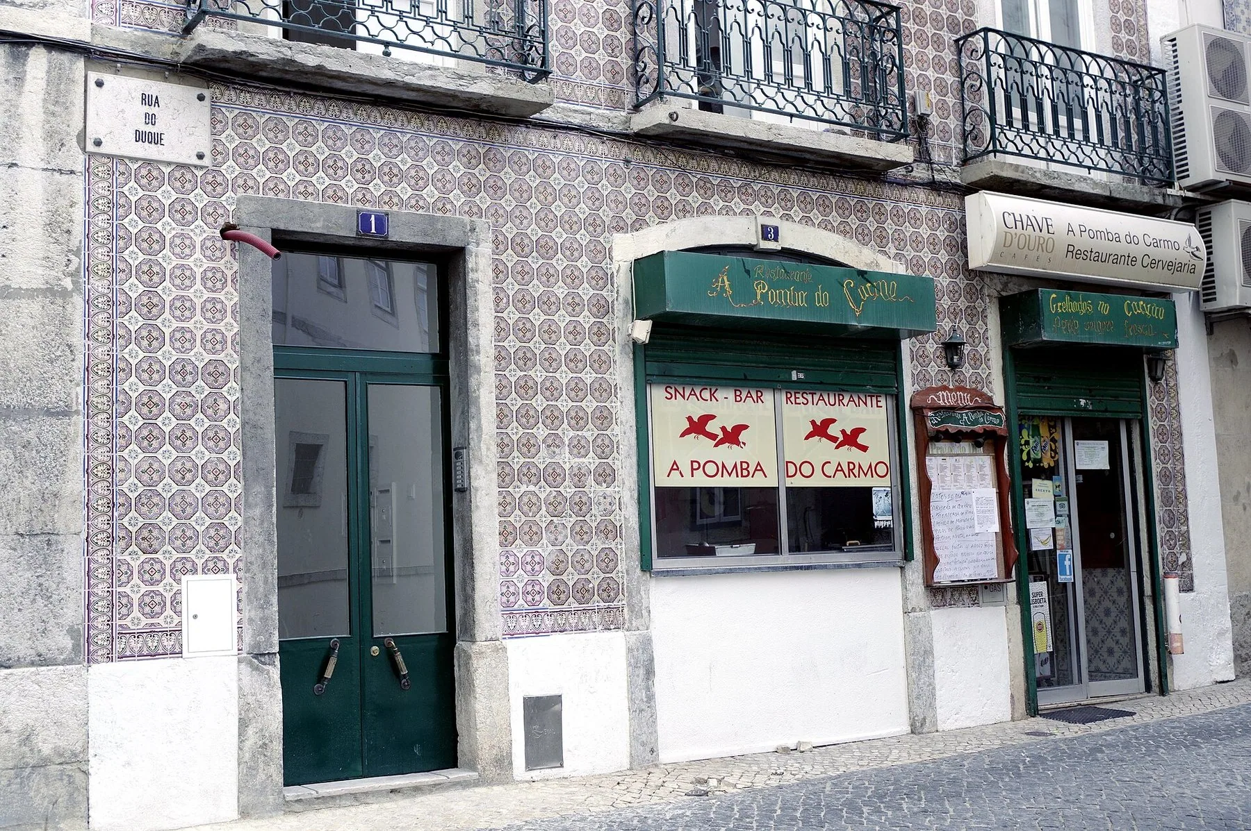 Husfasad klädd med azulejos, med portugisiska skyltar för snack-bar och restaurang