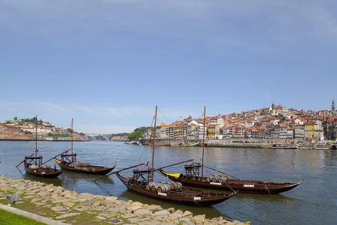 Rabelobåtar med vinfat förtöjda vid Douros södra strand, med Portos gamla stad på andra sidan floden