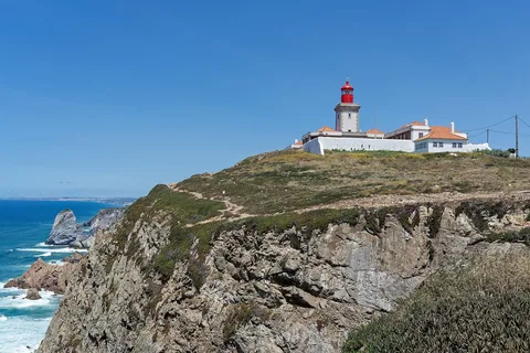 Fyren på Cabo da Roca uppe på klippkanten, med branta klippor och Atlanten i klar sikt nedanför