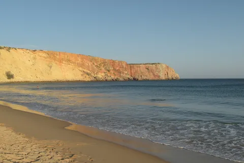 Sandstranden vid Mareta med en gyllene klippvägg till vänster och udden som sticker ut i havet bortom